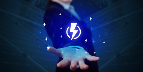 Hand in suit holding lightning bolt on his hand, green environment concept
