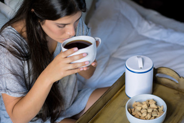 Young woman having breakfast in bed
