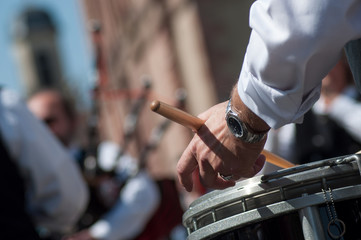 closeup of hand of drummer in scottish band playing in the street
