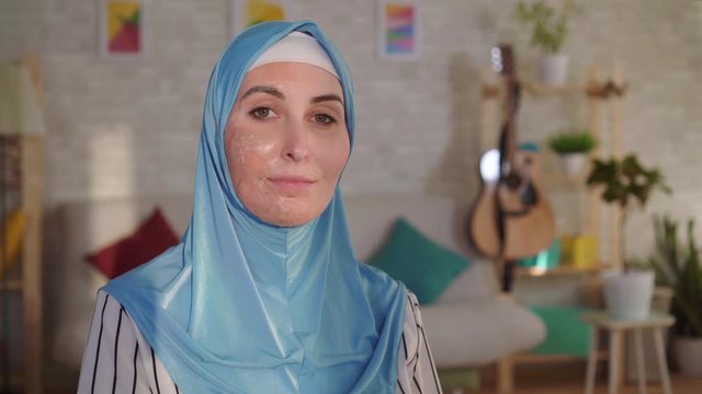 Smiling muslim woman in hijab with a burn scar on her face looking at the camera