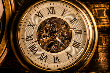 Fototapeta na wymiar Antique clock on the background of vintage books. Mechanical clockwork on a chain.