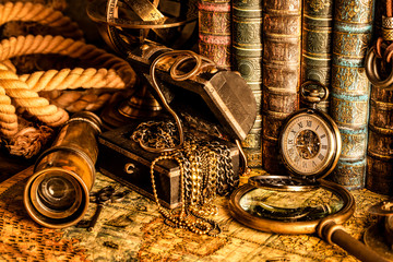 Antique clock on the background of a magnifying glass, treasure chest with gold and books. Vintage style. 1565 old map of the year.
