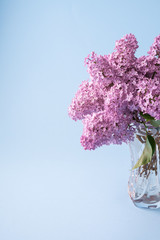 Lilac bouquet blooming in transparent crystal vase