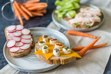 Healthy open sandwiches with vegetables , carrots , radish , cheddar cheese and turkey pastrami, cucumber on a wooden background , close up 