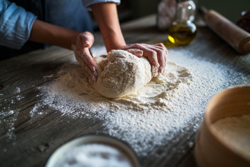 Hands knead the dough for pizza making. Fresh raw dough for pizza or bread baking on wooden board.