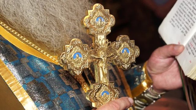 Christian Orthodox Church. The priest reads a prayer. Golden cross in the hands of a priest. Fixed camera (close-up)