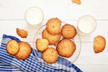 Sesame biscuits with milk for breakfast for children. Children's hands in the frame. Children eat biscuits. View from above.