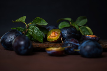 Plums in drops on a dark wood background. Toning. Selective focus.