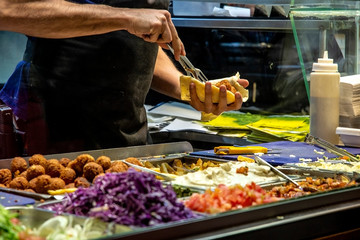 Preparation of a falafel dish, flafel balls and chopped vegetables on a store desk vegan food
