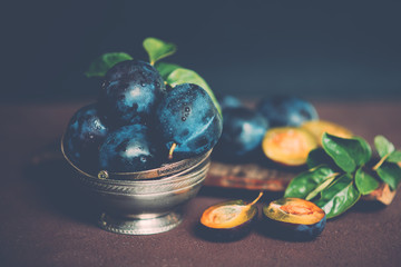 Bowl with ripe juicy plums on table. Fresh organic plums. Summer harvest. Autumn harvest. Beautiful still life. Toned image. Selective focus.
