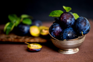 Bowl with ripe juicy plums on table. Fresh organic plums. Summer harvest. Autumn harvest. Beautiful still life. Toned image. Selective focus.