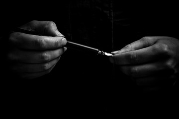 female hand elegantly holding an ink pen with a metal tip close-up on a black background. classic fountain pen isolated macro black and white. copy space