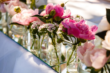pink wildflowers and lilac carnations in a vase with green eucalyptus stands on a wooden cut on a brown table with candles, on a background of a bouquet and groceries, wedding decor, party