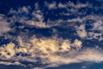 cumulus and cirrus clouds against the evening blue sunset sky