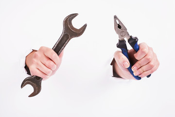 Pliers and wrench in the hand of a girl. Symbol of hard work, feminism and labor day. Isolate on white background.