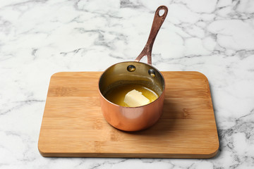 Saucepan with melting butter on marble table