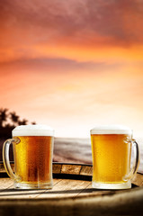 Cold fresh beer on barrel of wood. Summer sunset time. Sea landscape with beach and palms. Free space for your bottle. 