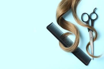 Flat lay composition with light brown hair, comb, scissors and space for text on color background....