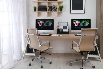 Modern workplace with large desk and computers in room. Stylish interior