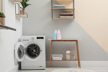 Modern washing machine in laundry room interior