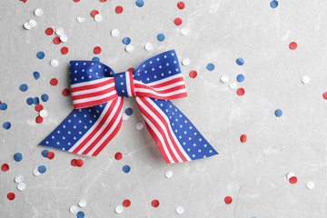 Obraz premium Ribbon bow with American flag pattern and confetti on light background, flat lay with space for text. USA Independence Day