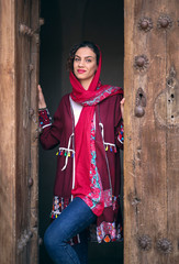 young beautiful iranian lady stepping out of an old house