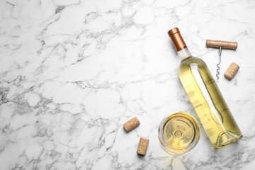 Fototapeta na wymiar Glass and bottle with white wine on marble background, flat lay. Space for text