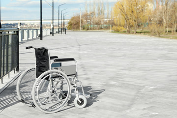 Empty wheelchair on embankment on sunny day. Space for text