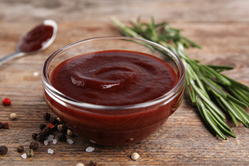 Composition with bowl of barbecue sauce on wooden table