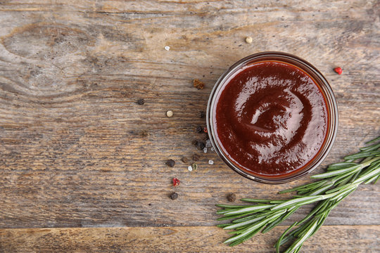 Flat lay composition with barbecue sauce on wooden background. Space for text