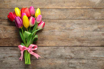 Beautiful bouquet of spring tulip flowers on wooden background, top view. Space for text