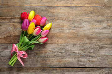 Beautiful bouquet of spring tulip flowers on wooden background, top view. Space for text