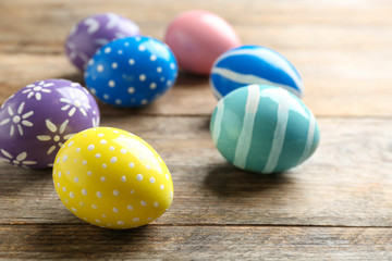 Fototapeta premium Painted Easter eggs on wooden table, space for text