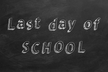 Hand drawing text "Last day of SCHOOL" on blackboard. 