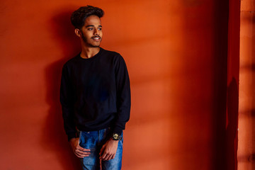Fototapeta na wymiar Indian man student photo male model fashion posing photoshoot photographer orange wall background