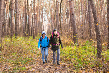 Fototapeta premium adventure, travel, tourism, hike and people concept - smiling couple walking with backpacks over autumn natural background