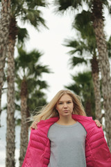 Portrait of beautiful blond girl posing for photo at the park with palm tree