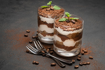two portions Classic tiramisu dessert in a glass on dark concrete background