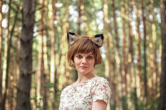 Woman with fox ears against the background of a pinewood