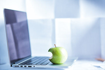 laptop and a bitten green apple on it