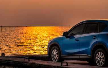 Fototapeta na wymiar Blue compact SUV car with sport and modern design parked on concrete road by the sea at sunset. Environmentally friendly technology. Electric car technology and business. Hybrid auto and automotive.
