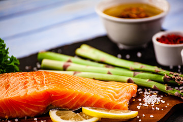 Fresh raw salmon fish served on black stone on wooden table
