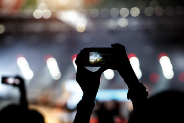 A mobile phone in the hands of fan at summer music show
