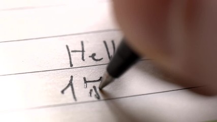 Beginner Chinese language learner writing Hello word Nihao in Chinese characters and pinyin on a notebook macro shot