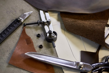 Leather crafting DIY tools and templates on workbench. Fittings and leather pieces with craft instruments for leather items manufacturing.