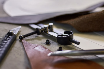 Leather crafting DIY tools and templates on workbench. Fittings and leather pieces with craft instruments for leather items manufacturing.