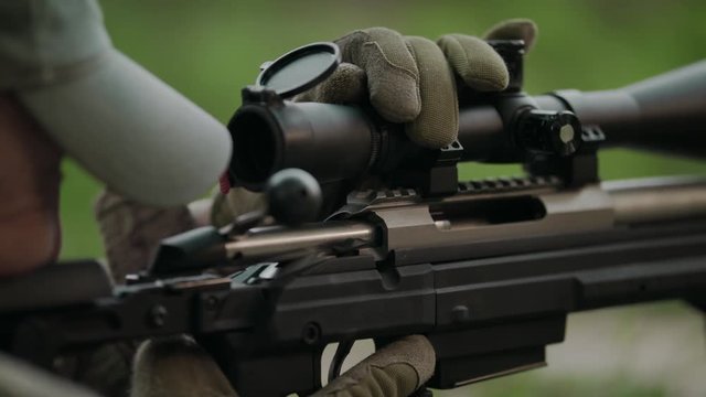 Sniper rifle. Hunter adjusts the scope. Slow Motion. 4K.