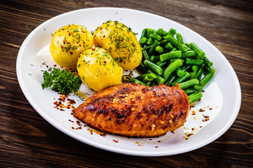 Grilled chicken fillet and vegetables on wooden table
