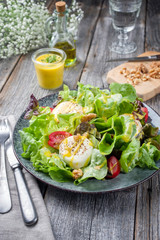 Traditional Germen summer lettuce with curled lettuce, goat cheese and mango dressing as closeup on a plate on a well laid table
