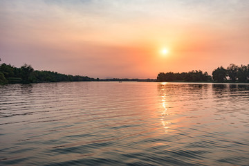 Hazy glowing sunset as the sun lowers into the hazy horizon - in Hoi An, Vietnam